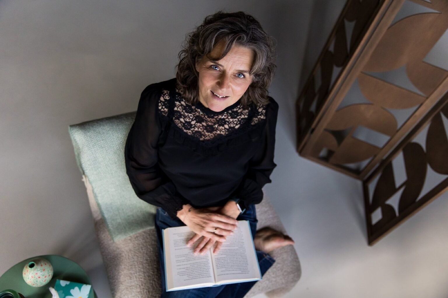 Nicole zit met een opengeslagen boek op schoot en kijkt omhoog