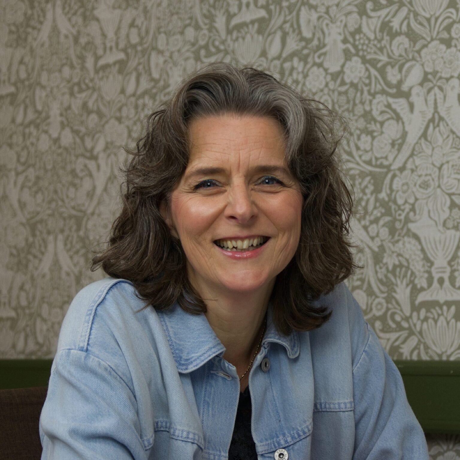Nicole Hoogenboom in een spijkerjasje voor een bloemenbehang